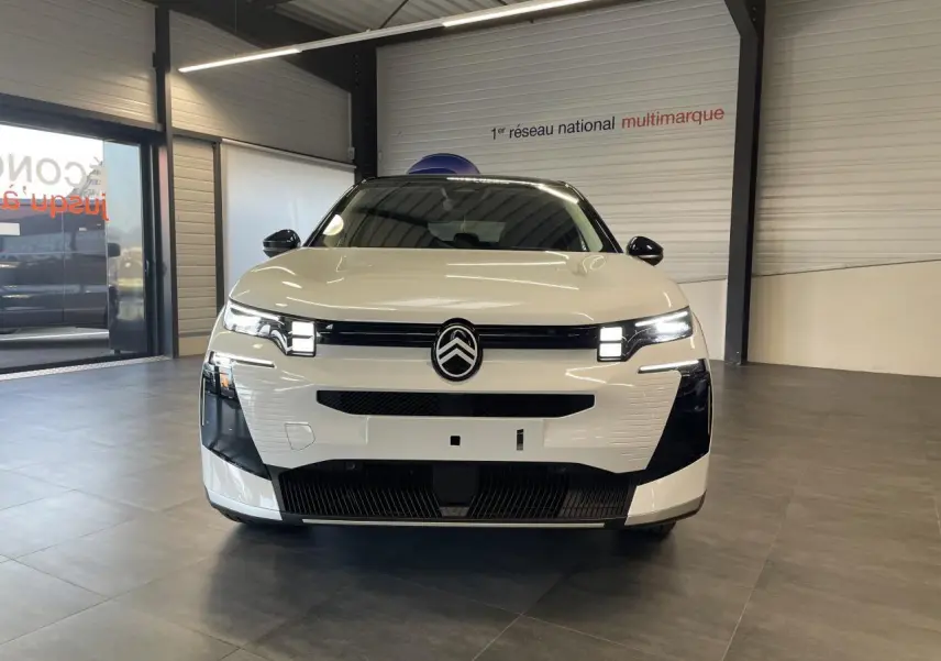 Vue avant d'un Citroën C5 Aircross blanc Okenite avec toit noir, calandre et phares LED distinctifs en showroom.