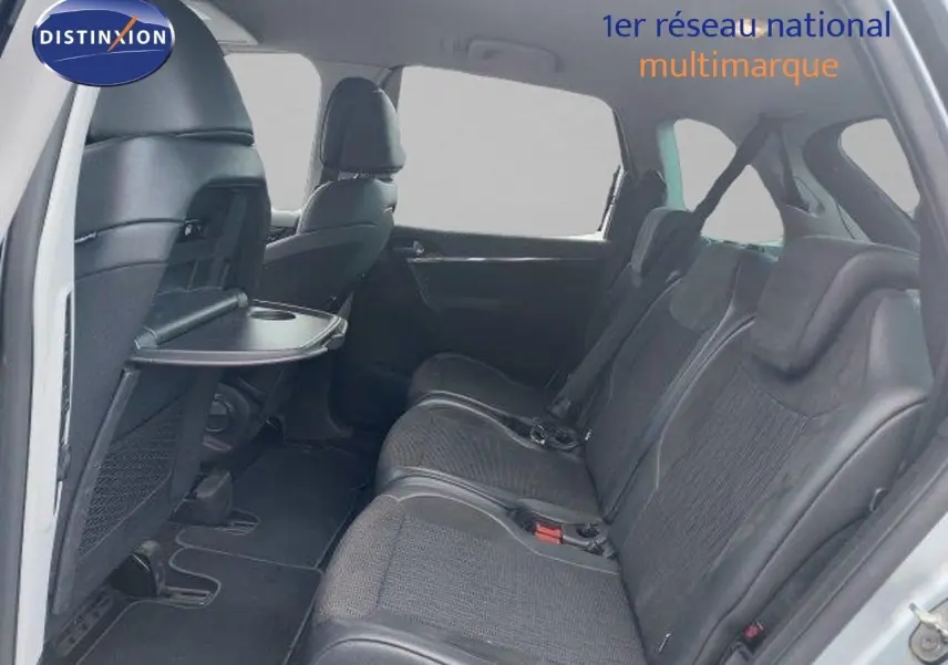 Vue intérieure côté droit arrière de la Citroën C4 Picasso gris alu, sièges en cuir noir avec tablette rabattable.