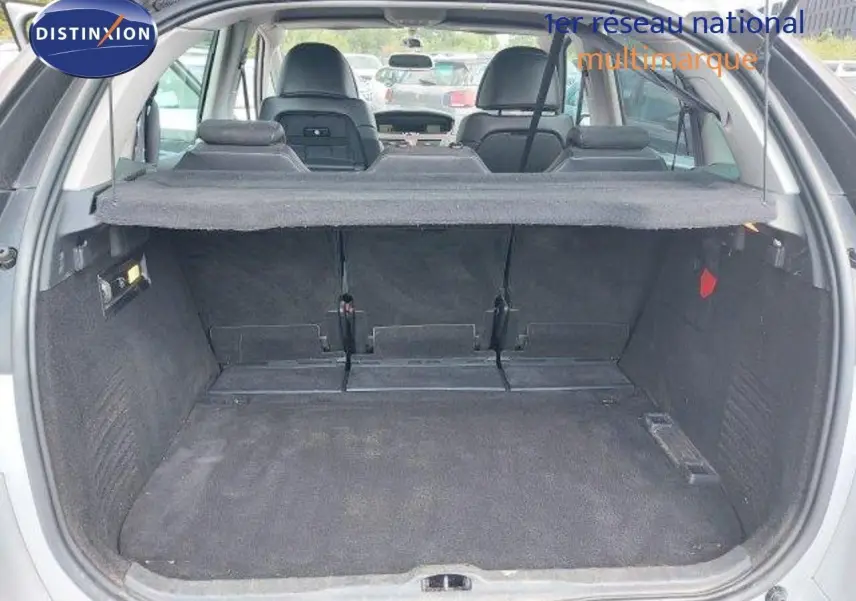 Coffre ouvert d'une Citroën C4 Picasso gris alu métal, vue arrière montrant l'espace de chargement et les sièges rabattus.