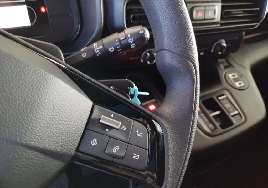 Gros plan sur le volant et la commande multifonction du Citroën Berlingo Van gris acier 2025 côté gauche.