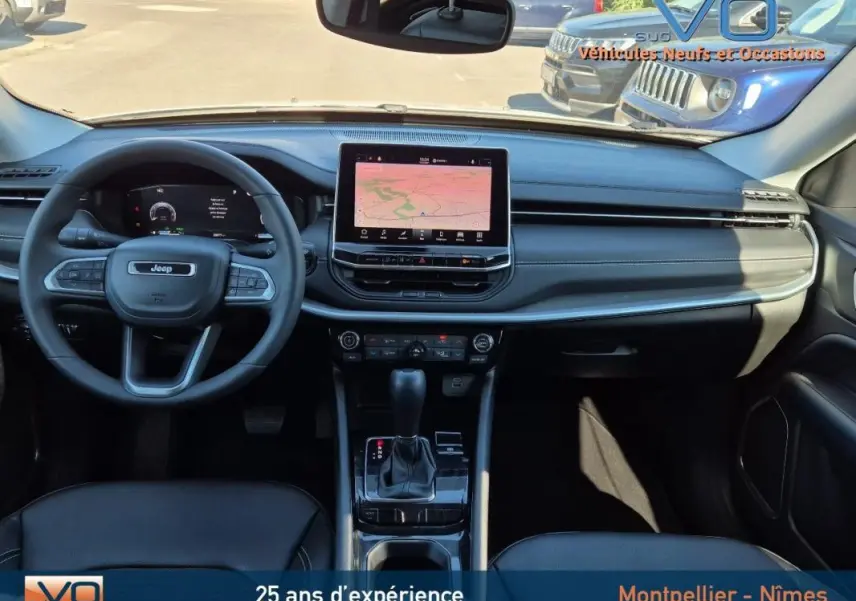 Vue intérieure frontale du tableau de bord noir du Jeep Compass 2023 avec écran tactile central et volant multifonction.