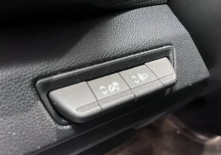 Gros plan sur les commandes de réglage des phares et du tableau de bord du Renault Trafic Fourgon gris foncé.