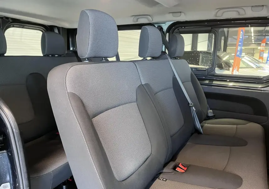 Vue intérieure côté droit sur la banquette arrière grise du Renault Trafic Fourgon 2023 avec vitres latérales ouvertes.
