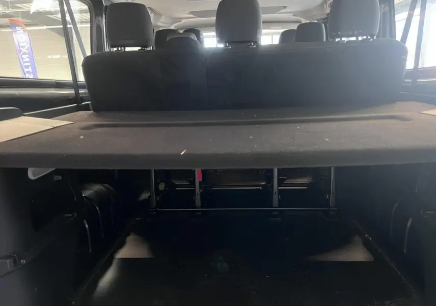 Vue arrière intérieure du Renault Trafic Combi gris foncé, montrant la banquette arrière et le cache-bagages déployé.