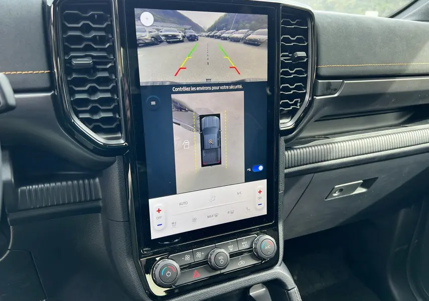 Vue rapprochée de la console centrale du Ford Ranger Wildtrak noir, avec écran tactile affichant la caméra 360° et commandes climatisation.