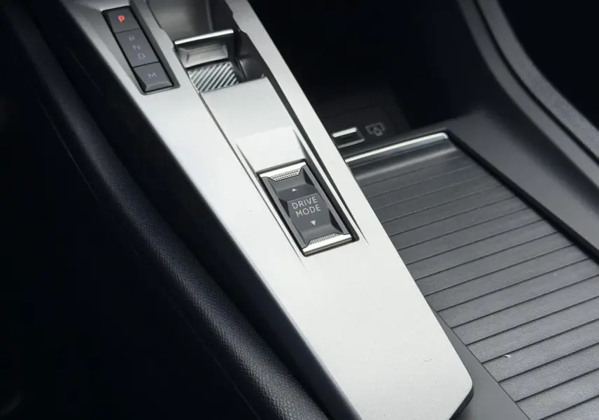 Gros plan sur la console centrale argentée du Peugeot 308 NV Hybrid 145 GT avec bouton Drive Mode et commandes de boîte auto.
