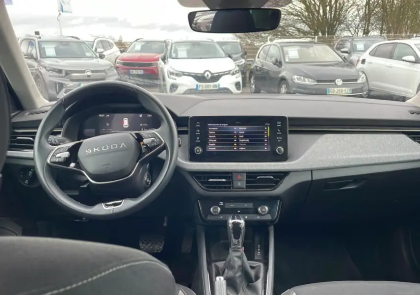 Vue intérieure avant du Skoda Kamiq 2025 avec tableau de bord noir et écran tactile central allumé.