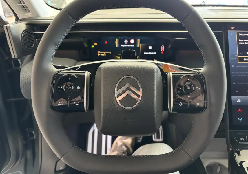 Vue intérieure centrée sur le volant noir du Citroën C5 Aircross 2026 avec commandes tactiles et tableau de bord numérique.