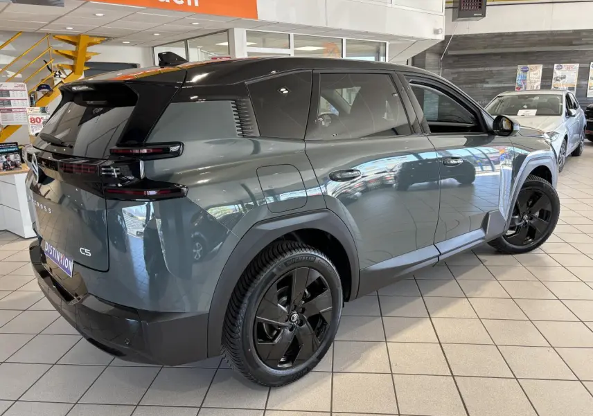 Vue 3/4 arrière droite du Citroën C5 Aircross vert métallisé avec toit noir et jantes alliage noires en showroom.