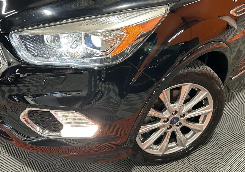 Gros plan sur l’avant droit noir du Ford Kuga 2017, mettant en valeur le phare allumé et la jante en alliage.