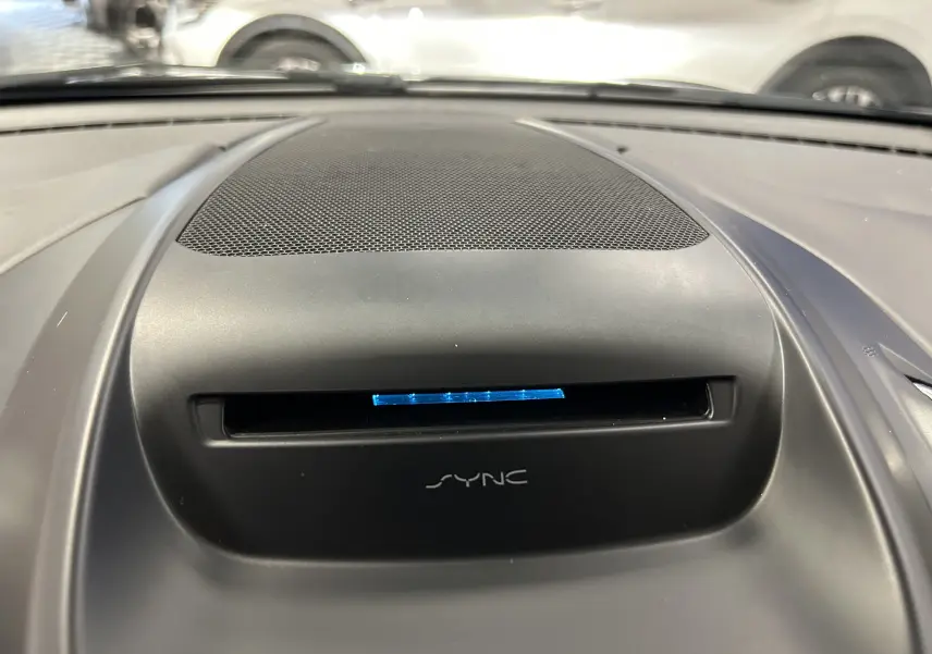 Gros plan sur le haut de la planche de bord noire du Ford Kuga 2017 avec écran SYNC illuminé en bleu.