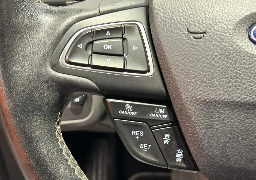 Gros plan sur les commandes multifonctions noires du volant en cuir noir du Ford Kuga 2017, version Vignale.