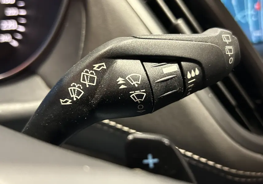 Gros plan sur la commande de l'essuie-glace du Ford Kuga noir, avec pictogrammes blancs visibles sur levier noir.
