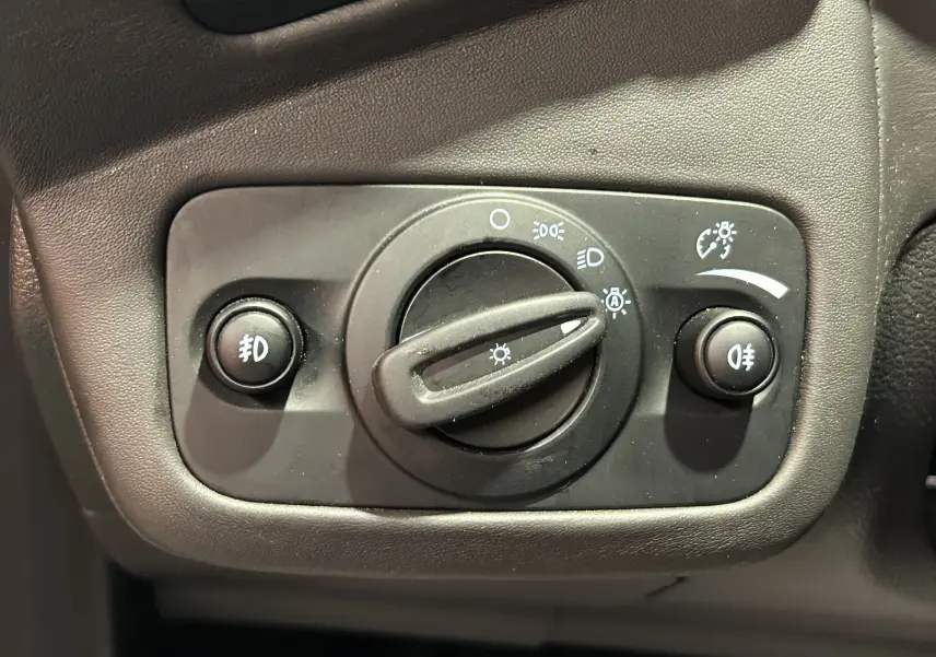 Gros plan sur la commande d’éclairage noire du tableau de bord d’un Ford Kuga noir, avec boutons et molette.