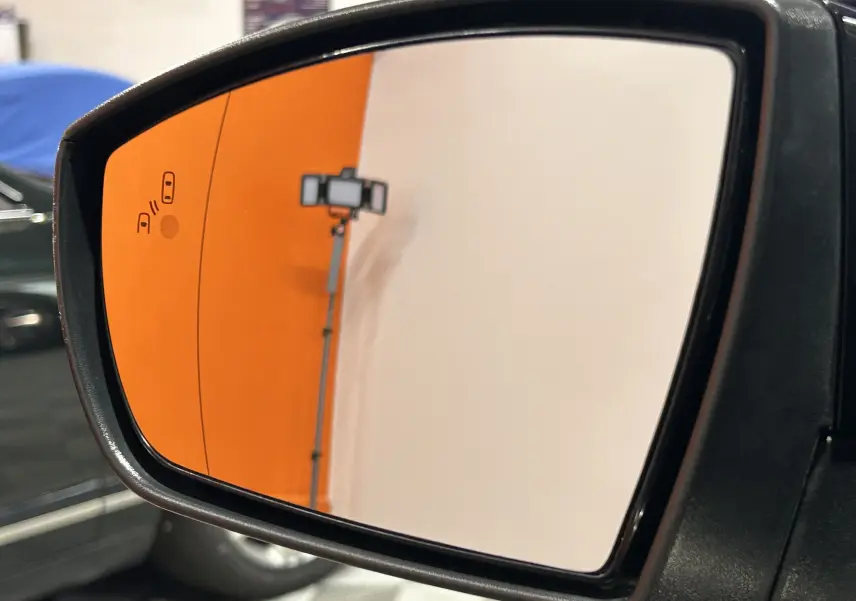 Gros plan sur le rétroviseur droit noir du Ford Kuga 2017, reflétant un mur orange et blanc en intérieur.