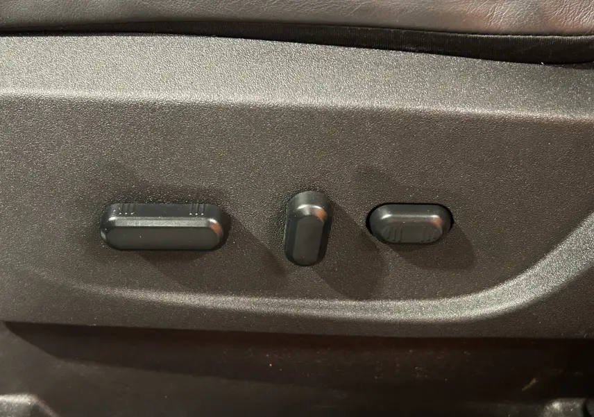 Gros plan sur les commandes électriques de réglage du siège en cuir noir du Ford Kuga TDCI 180 BVA Vignale 2017.