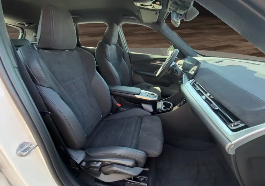 Intérieur avant droit du BMW X1 blanc 2025, sièges sport M Sport en alcantara noir et tableau de bord moderne.