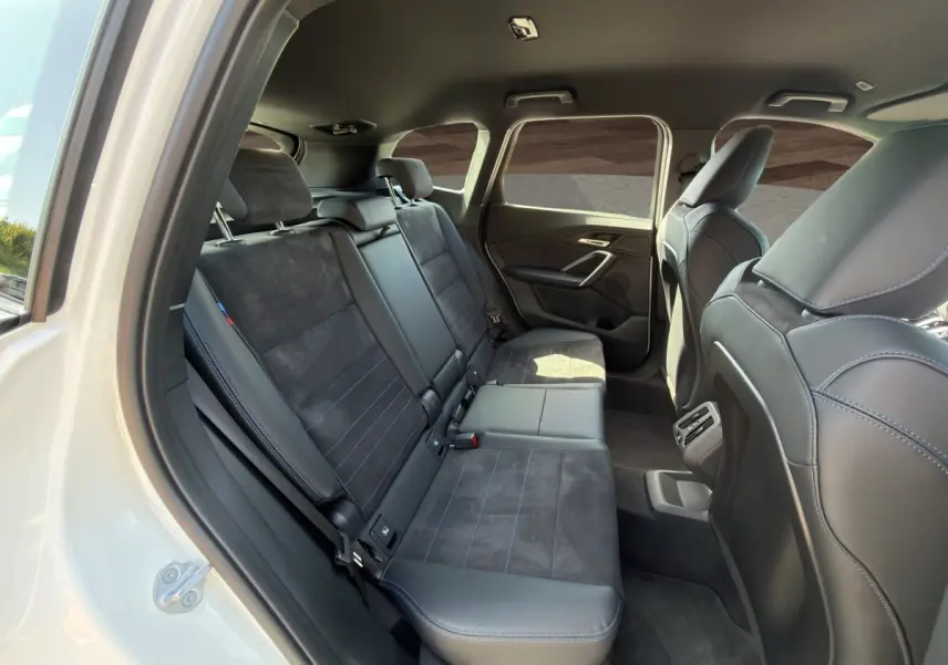 Vue intérieure côté droit des sièges arrière en cuir noir et alcantara avec surpiqûres bleues d’un BMW X1 blanc 2025.