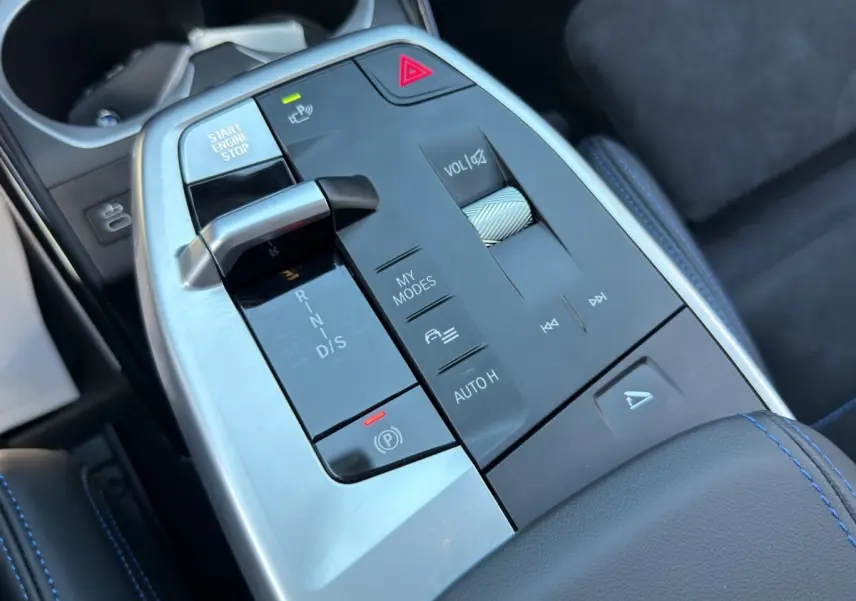 Gros plan sur la console centrale du BMW X1 blanc 2025, montrant levier de vitesses et commandes en aluminium.