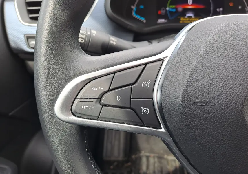 Gros plan sur les commandes de régulateur de vitesse au volant noir du Renault Arkana 2023 hybride.