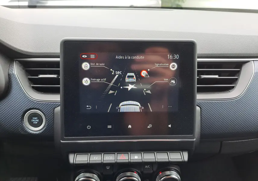 Écran central du tableau de bord du Renault Arkana 2023 affichant les aides à la conduite, avec boutons de commande en dessous.