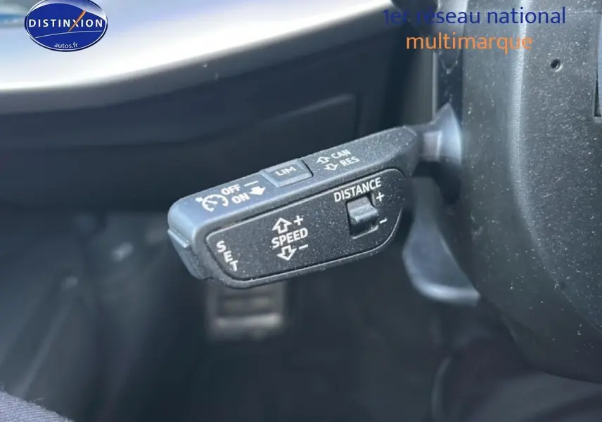 Gros plan sur la commande de régulateur de vitesse au volant d'une Audi A3 Sportback noire 2024.