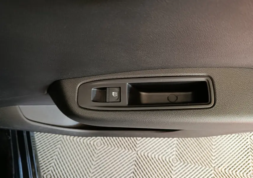 Gros plan sur la commande de lève-vitre électrique côté gauche de la porte intérieure noire d'une Renault Clio 2025.