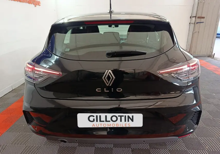 Vue arrière d'une Renault Clio noire Evolution Blue dCi 100 -25 avec feux LED allumés en intérieur showroom.