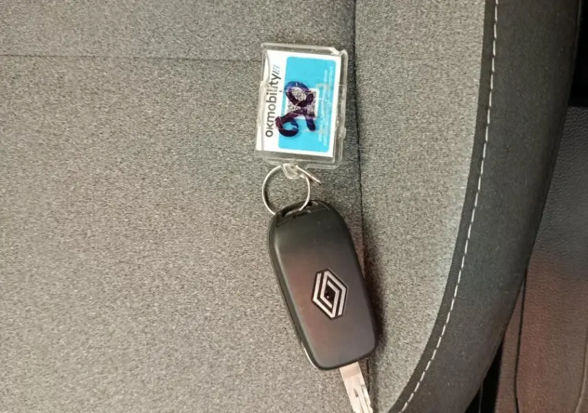 Clé Renault posée sur un siège tissu gris avec surpiqûres blanches, intérieur sobre et fonctionnel.