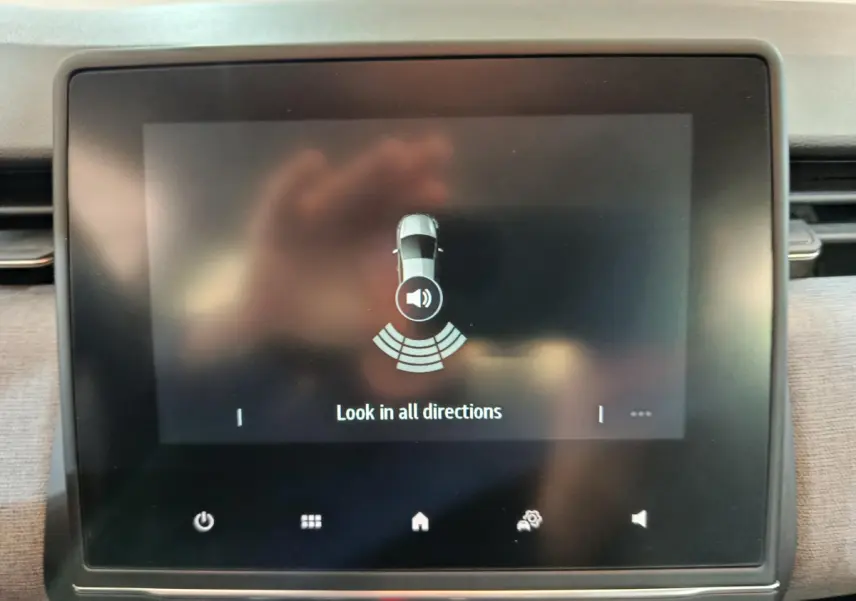 Écran tactile central de la Renault Clio 2025 affichant l'alerte de détection d'obstacles en stationnement.