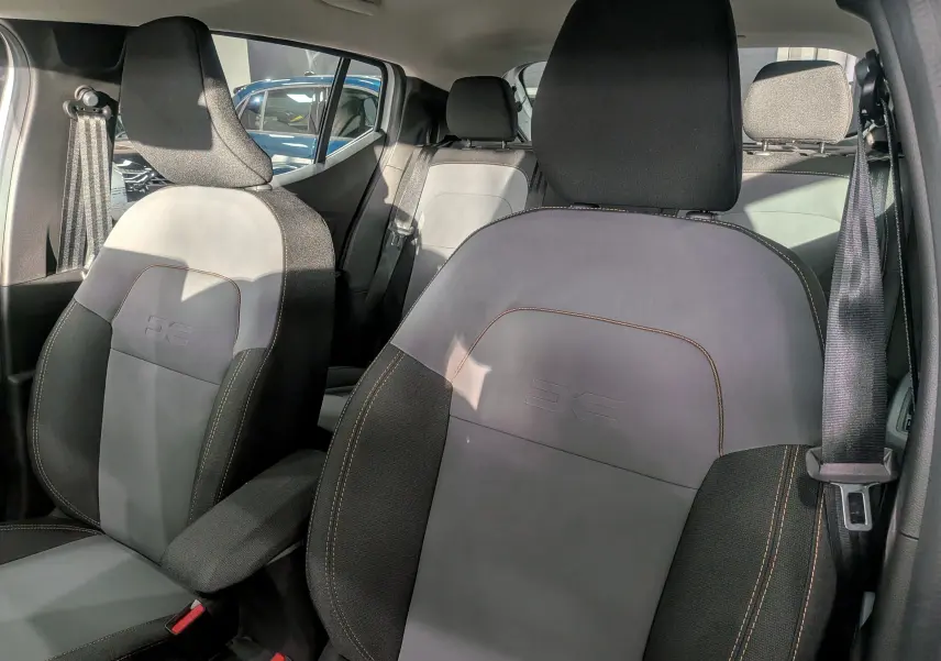 Vue intérieure des sièges avant en tissu gris et noir avec surpiqûres orange de la Dacia Sandero Stepway 2025.