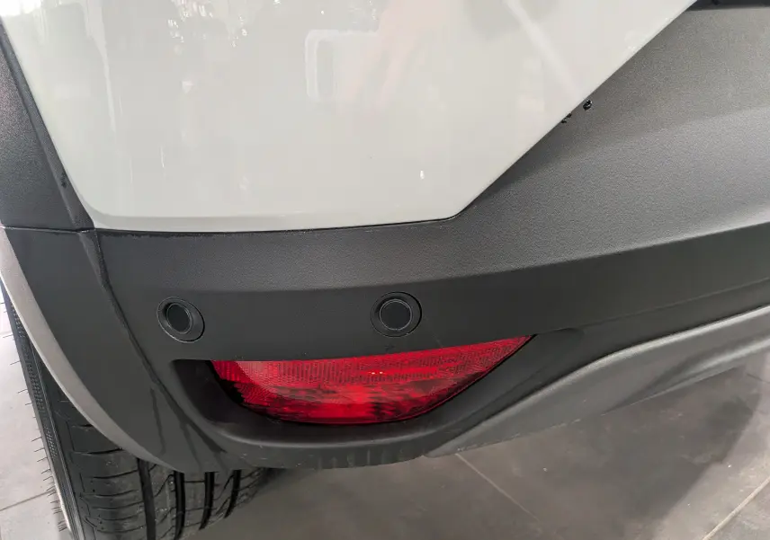 Gros plan sur le feu arrière droit rouge et le pare-chocs noir du Dacia Sandero Stepway blanc glacier.