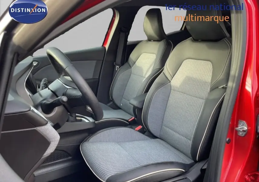 Vue intérieure côté conducteur de la Renault Clio rouge Désir Métal 2025, sièges tissu gris avec surpiqûres blanches.