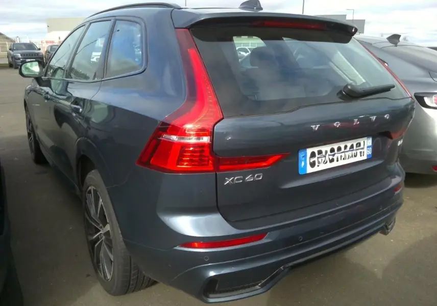 Vue 3/4 arrière droite d'un Volvo XC60 bleu avec feux arrière en forme de L et jantes alliage 20 pouces.