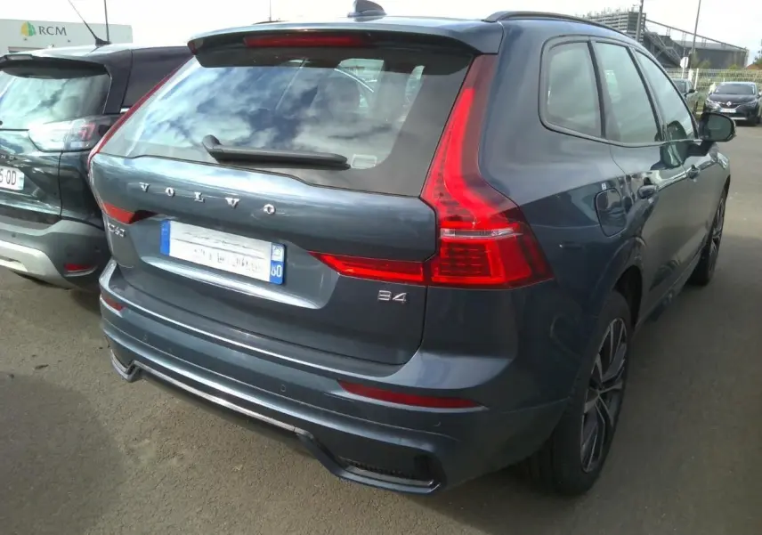 Vue 3/4 arrière droite d'un Volvo XC60 bleu avec feux arrière en forme de L et jantes alliage 20 pouces.
