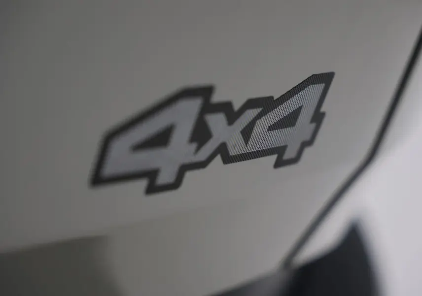 Gros plan sur l’inscription 4x4 en noir et gris sur la carrosserie couleur Sandstone du Dacia Duster 2024.