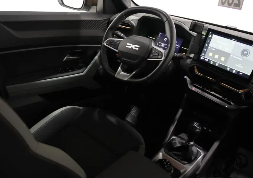 Vue intérieure côté conducteur du Dacia Duster 2024 avec volant multifonction, écran tactile et levier de vitesses manuel.