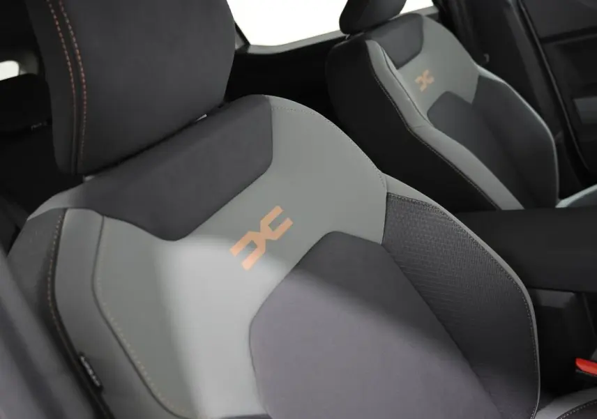 Gros plan sur les sièges avant gris et noirs du Dacia Duster 2024 avec logo orange et surpiqûres contrastées.