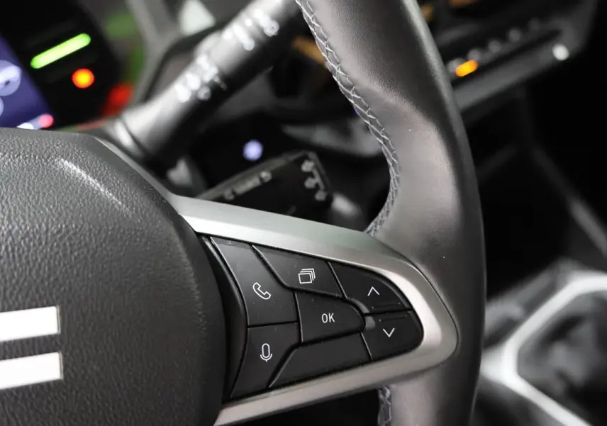 Gros plan sur le volant en cuir noir du Dacia Duster 2024, montrant les commandes multifonctions côté droit.