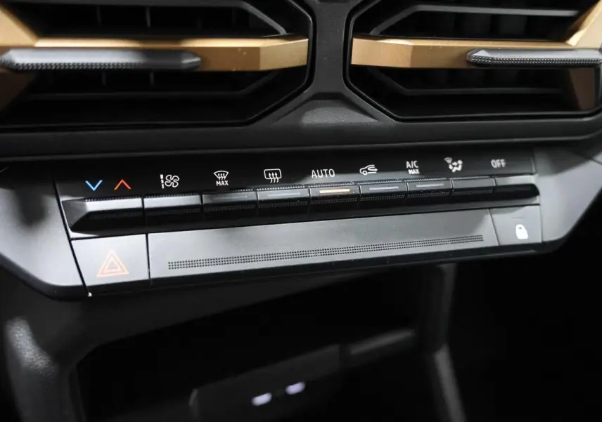 Gros plan sur la console centrale du Dacia Duster 2024, boutons de climatisation et ventilation avec inserts couleur sandstone.