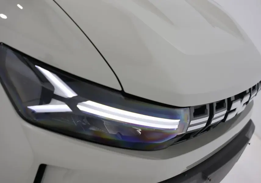 Gros plan sur le phare avant gauche et la calandre du Dacia Duster 2024 couleur Sandstone.