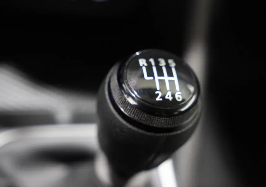 Gros plan sur le levier de vitesses manuel du Dacia Duster TCE 130 4x4, intérieur sombre.