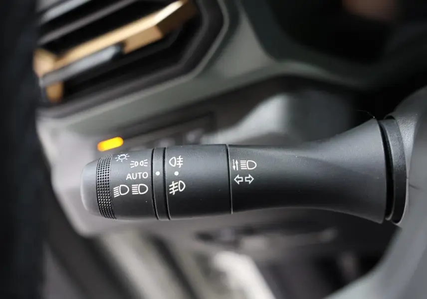 Gros plan sur la commande des phares et clignotants du Dacia Duster 2024, intérieur noir.