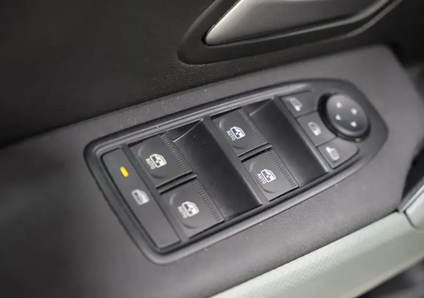 Gros plan sur les commandes de lève-vitres et réglage des rétroviseurs intérieures du Dacia Duster 2024.