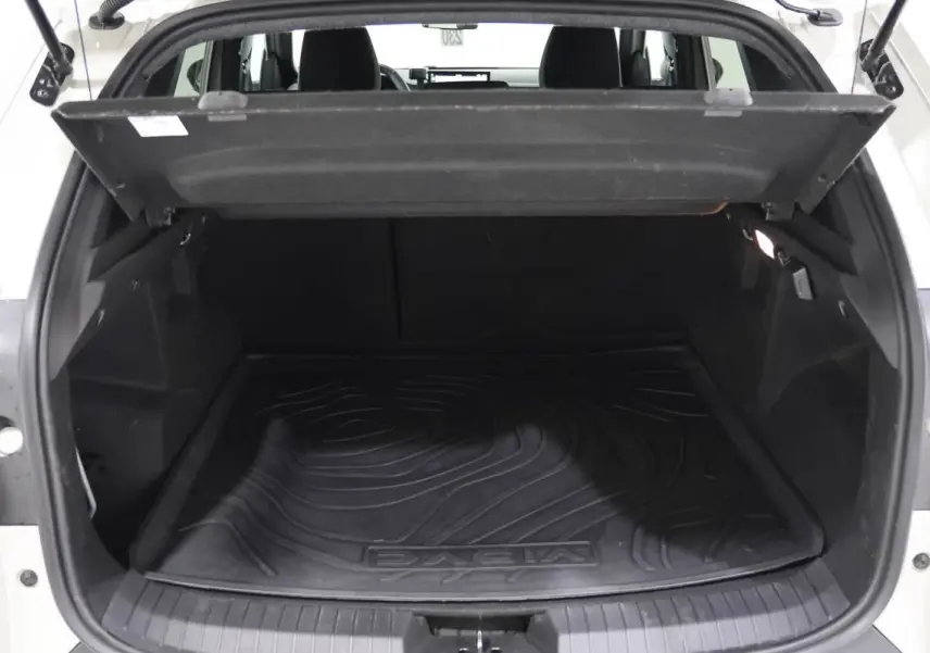 Coffre ouvert vu de l'arrière d'un Dacia Duster 2024 couleur Sandstone, tapis de coffre noir avec logo Dacia visible.