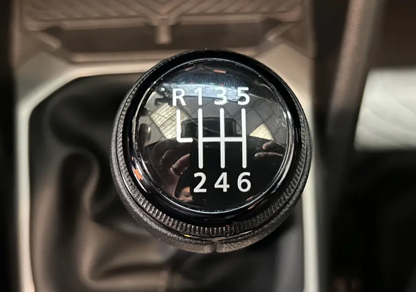 Gros plan sur le pommeau de la boîte manuelle du Dacia Duster 2024, avec marquage des six vitesses et marche arrière.