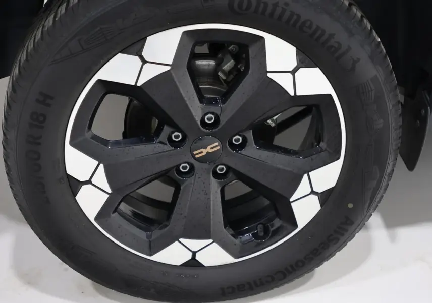 Gros plan sur la jante noire et blanche du Dacia Duster TCE 130 4x4 Extreme couleur Sandstone, pneus Continental.