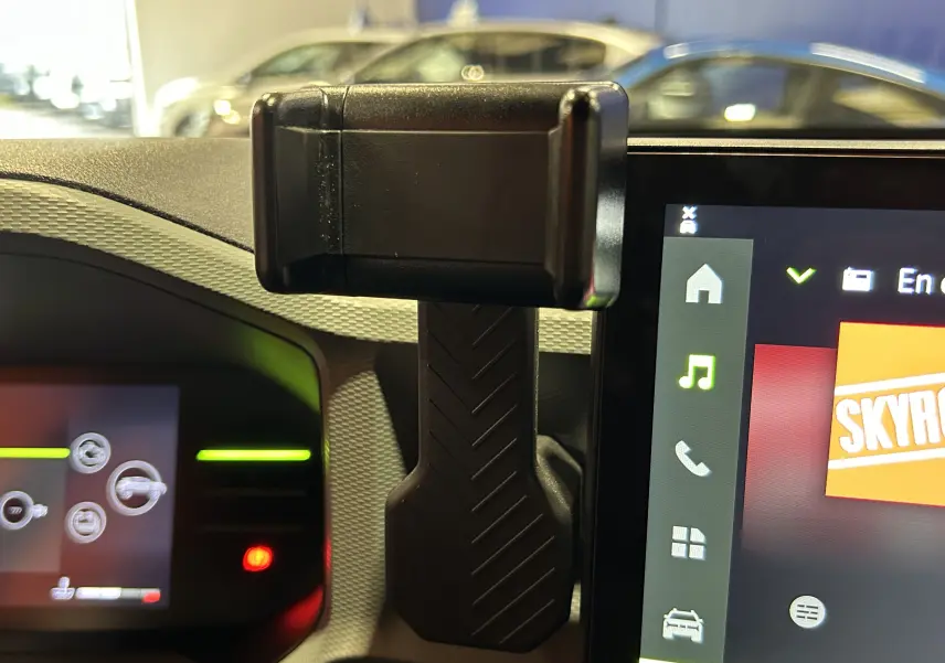 Vue intérieure du tableau de bord du Dacia Duster 2024 avec support téléphone et écran tactile multimédia allumé.
