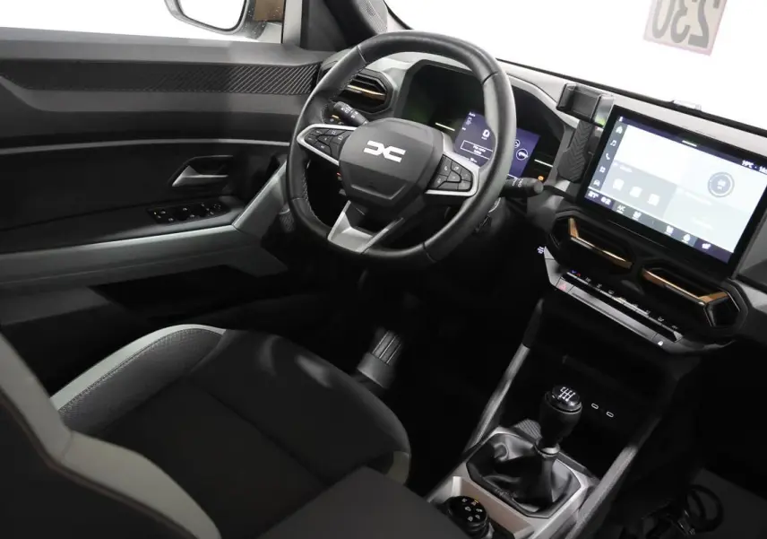 Vue intérieure côté conducteur du Dacia Duster 2024 avec volant multifonction et écran tactile central.