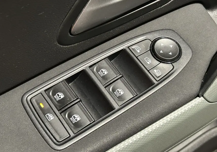 Gros plan sur les commandes électriques des vitres et rétroviseurs côté conducteur du Dacia Duster 2024 couleur Sandstone.